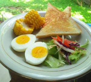 a plate of food with eggs and a salad and corn at Condro Wulan Hostel in Malang