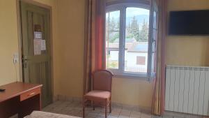 a room with a window and a chair and a desk at Auberge les Aromes in Grasse