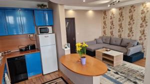 a kitchen with blue cabinets and a table and a couch at Boutique Apartment Jana in Shumen