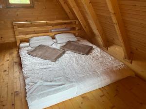 ein Bett in einem Blockhaus mit zwei Kissen darauf in der Unterkunft Vikendica Joža in Jajce