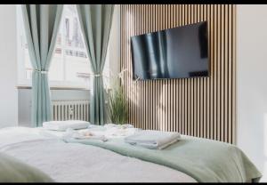 uma cama com toalhas e uma televisão na parede em Ferienwohnung Zentrum Erding em Erding