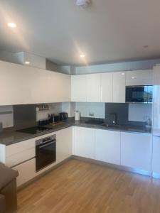 a kitchen with white cabinets and black appliances at CP Top floor luxury studio with spa and pool in Gibraltar