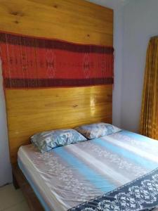una cama con cabecero de madera y dos almohadas en Pauls Homestay, en Wado