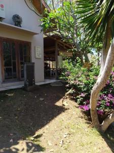 uma casa com uma palmeira e flores em frente em Pauls Homestay em Wado