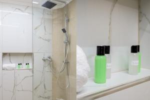 un bagno con doccia e una bottiglia verde su una mensola di Cosy Urban Escape a Alexandroupoli