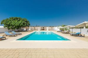 Una piscina con sillas y sombrillas en un patio. en Masseria Pepe, en Torre Ovo