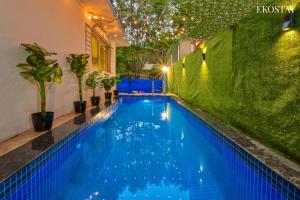 a swimming pool in a backyard with a green wall at EKOSTAY - Omega Villa in Igatpuri
