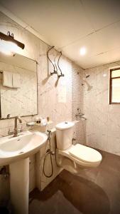 La salle de bains est pourvue de toilettes blanches et d'un lavabo. dans l'établissement GEETANJALI REGENCY, à kolkata