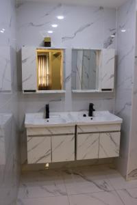 a white bathroom with two sinks and a mirror at Amman Trail Hostel in Amman