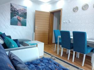 uma sala de estar com uma mesa e cadeiras azuis em EMA LUX - zgrada Panorama em Sokobanja