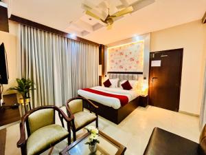 ein Hotelzimmer mit einem Bett und zwei Stühlen in der Unterkunft Hotel Ramawati Near Ganga Ghat in Haridwar