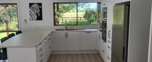 biała kuchnia ze zlewem i oknem w obiekcie Dewdrop Cottage w mieście Hastings