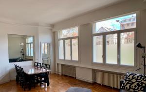 a dining room with a table and some windows at GRAND APPARTEMENT de 120 m2 à 5 minutes du Metro 7 lits in Les Lilas