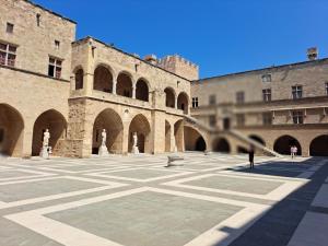 een grote binnenplaats met een gebouw met bogen bij The Retreat in the heart of Old Town Rhodes in Rhodos-stad