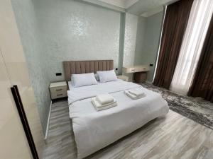 a bedroom with a large white bed with two towels on it at Modern Spaces 2 in Yunusobod