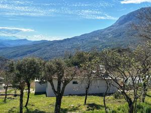 une maison dans un champ avec des montagnes en arrière-plan dans l'établissement Georgaras Accommodation, à Platanoússa