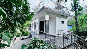Casa blanca con balcón y coche en Shivas Farmhouse, en Sultan Bathery