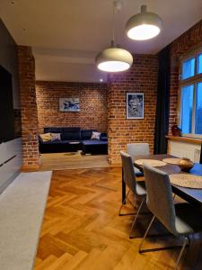 een woonkamer met een bakstenen muur en een tafel en stoelen bij Riverside Retreat on Parkowa in Wrocław