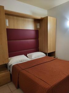 a bedroom with a bed with a red headboard at Hotel Mondial in Lido di Jesolo