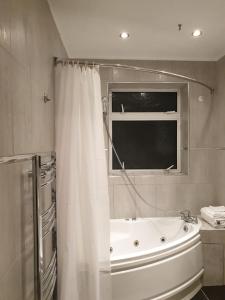 a bathroom with a bath tub and a window at Rooms at EEJ homes in London