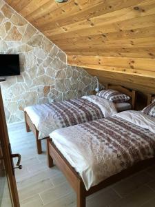 duas camas num quarto com uma parede de pedra em Vila Djekic em Andrijevica