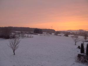 a snow covered field with a sunset in the background at Schmidt`s Eppelborner Ferienwohnung in Eppelborn