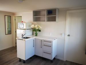 a white kitchen with a sink and a vase of flowers at Warm little house at Wesley in Auckland