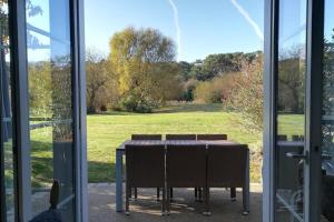 een tafel met stoelen voor een glazen deur bij "LA MAISON DU BOCAGE" Maison 6 personnes, accès piscines, résidence privée in Talmont