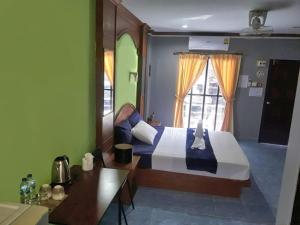 a bedroom with a bed and a table and a window at The Guest House in Patong Beach