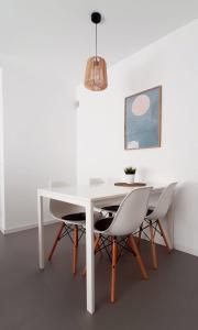 una mesa de comedor blanca con sillas y una lámpara de araña en Holidays Calella Ideal teletrabajo en Calella