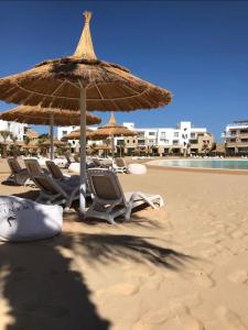 a group of chairs and an umbrella on the beach at El Gouna Swan Lake I Direct Lake View I 3 Master Bedrooms Chalet in Hurghada