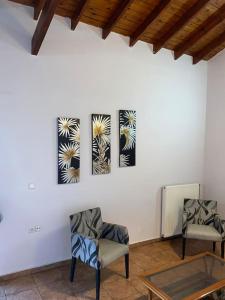 two chairs in a room with two paintings on the wall at Μεζονέτα Αιγαίο in Chios