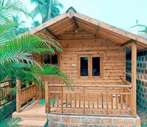 eine Holzhütte mit einer Veranda und einer Palme in der Unterkunft TP cottages Beach Resort in Arambol