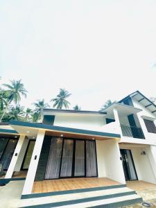 a large white house with palm trees in the background at Eleven villa 1 in Pangandaran