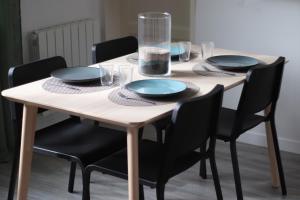 a wooden table with black chairs and plates on it at Top Appart - Parc Expo- Proche Musée de l Air- Proche parc Astérix in Le Blanc-Mesnil