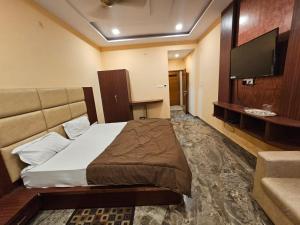 um quarto de hotel com uma cama e uma televisão de ecrã plano em Hotel Aditya Inn em Varanasi