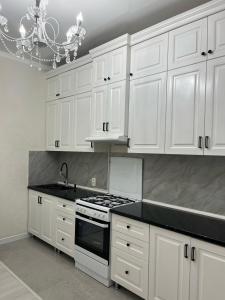 a white kitchen with white cabinets and a stove at 3-комнатные Апартаменты LUX in Taraz