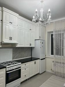 a kitchen with white cabinets and a chandelier at 3-комнатные Апартаменты LUX in Taraz