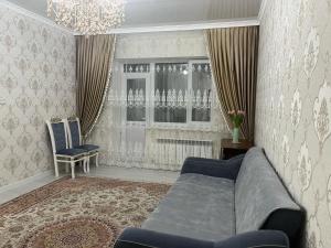 a living room with a couch and a window at 3-комнатные Апартаменты LUX in Taraz