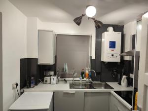 una cocina con armarios blancos y fregadero en home from home, en Erith