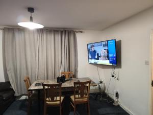 a dining room with a table and a tv on the wall at home from home in Erith