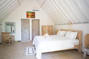 a bedroom with a white bed with a doll on it at Jepun Didulu Cottages in Candidasa
