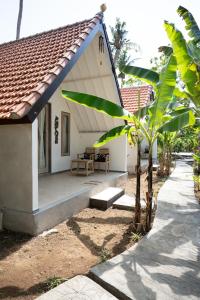 a small white house with a porch and a tree at Jepun Didulu Cottages in Candidasa