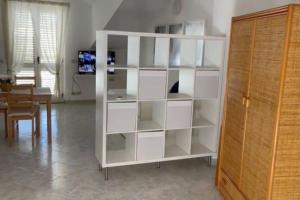 a white book shelf in a living room with a table at Appartamento incantevole, Soverato in Soverato Marina