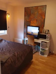 a bedroom with a bed and a desk with a television at CASA Mama total in Bodø