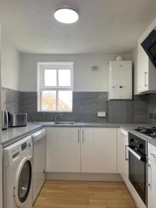 eine weiße Küche mit einer Waschmaschine und einem Fenster in der Unterkunft 2Bed Cozy Spacious apartment - 15min to Canary Wharf O2 Excel Central London in London