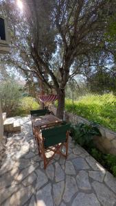 a picnic table under a tree on a stone patio at Holiday apartment near the sea in Melission