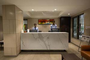 two men standing at a reception desk in a lobby at Freesia Residency by Express Inn in Nashik