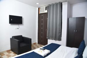 a bedroom with a bed and a chair and a television at Hotel Orchid INN at Budget Bazaar Janakpuri in New Delhi
