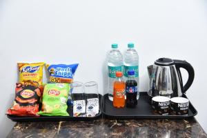 two black trays with snacks and water bottles on them at Hotel Orchid INN at Budget Bazaar Janakpuri in New Delhi